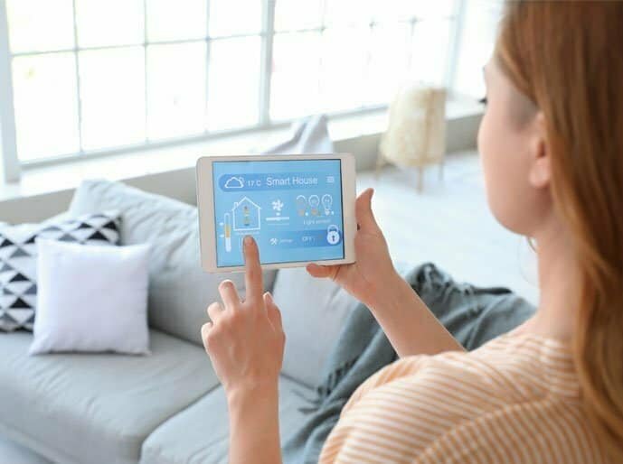 A woman uses a tablet with a smart home interface
