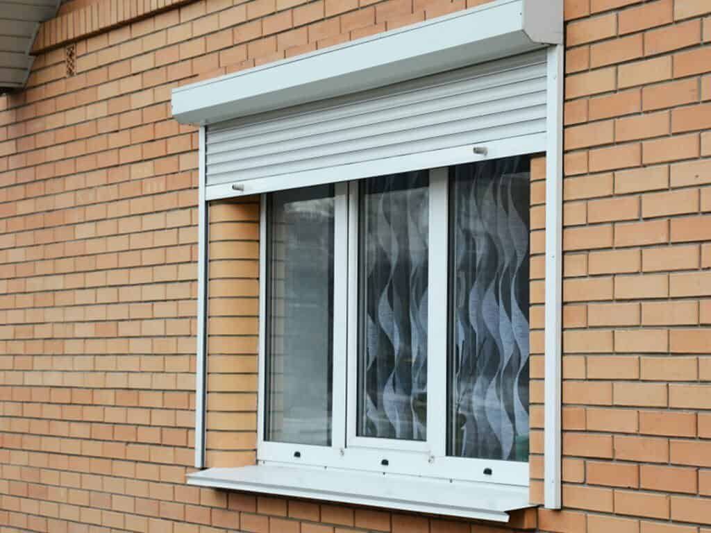 Window with closed rolling shutter on a brick wall.