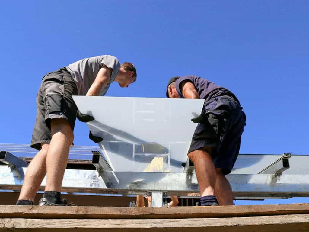 Two men installing a solar panel on a roof.