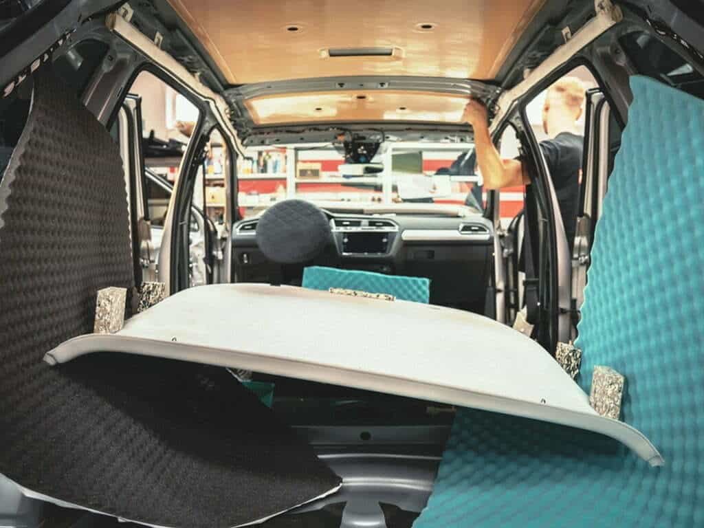 A car's interior is being soundproofed with acoustic foam and insulation.
